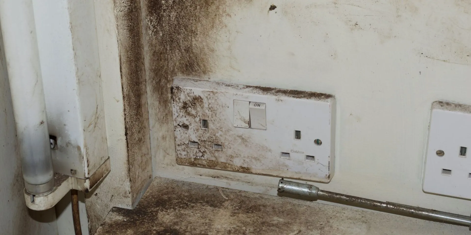 Mould and grime contamination around a wall socket before sanitation in Manenberg